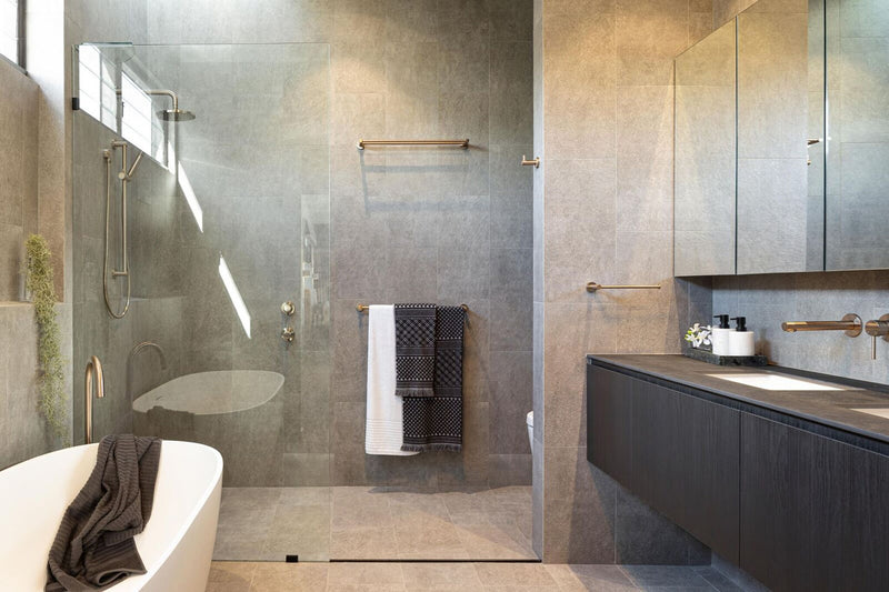 Badkamer met bad en douche met rosé gouden afwerkingen